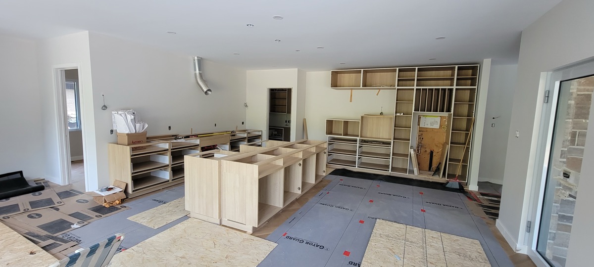 Kitchen cabinet installation in Vancouver underway — bare cabinet boxes and an unfinished shelving wall